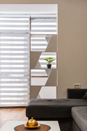 Un salon moderne avec un canapé d’angle, un meuble mural décoratif aux motifs géométriques et une plante en pot.