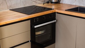 Een keuken met een inbouwoven, een zwart inductiekookveld en houten aanrechtbladen.