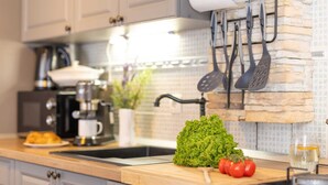 Una cucina con un piano di lavoro in legno, una macchina da caffè, un lavello e un porta utensili a sospensione.