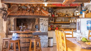 Una cucina rustica con sgabelli in legno, una parete in pietra e diversi utensili da cucina appesi sopra.