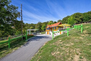 A building with a red roof and yellow walls, a paved path leading to it, and a green fence.