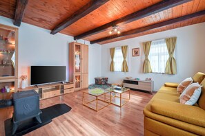 A modern living room with a wooden ceiling, a flat-screen TV, a sofa, a coffee table, and a cabinet.
