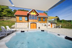 Ett hus med en swimmingpool, utomhusmöbler och en täckt uteplats.