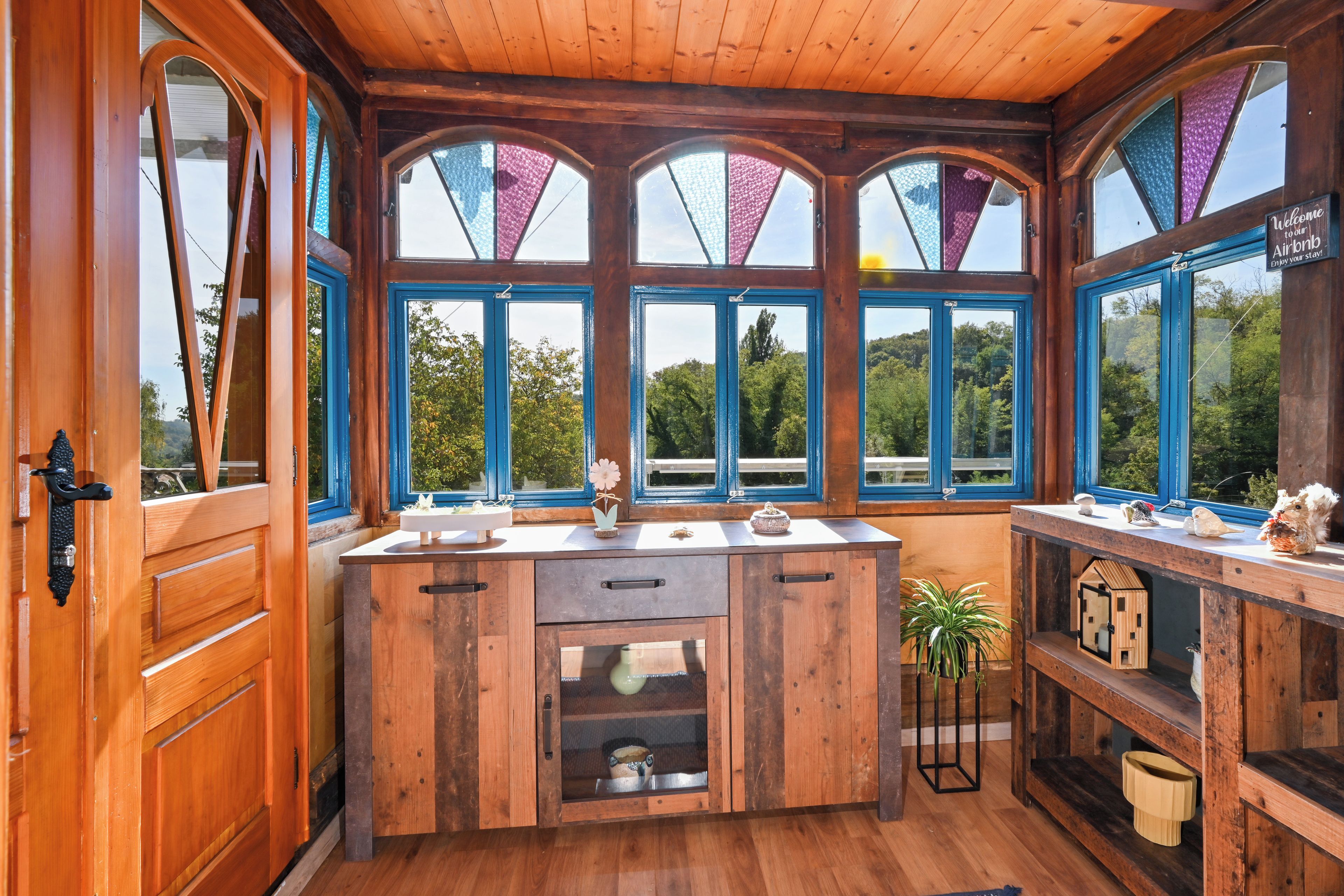 Uma cabana de madeira com cozinha central, várias janelas e vista para o exterior.