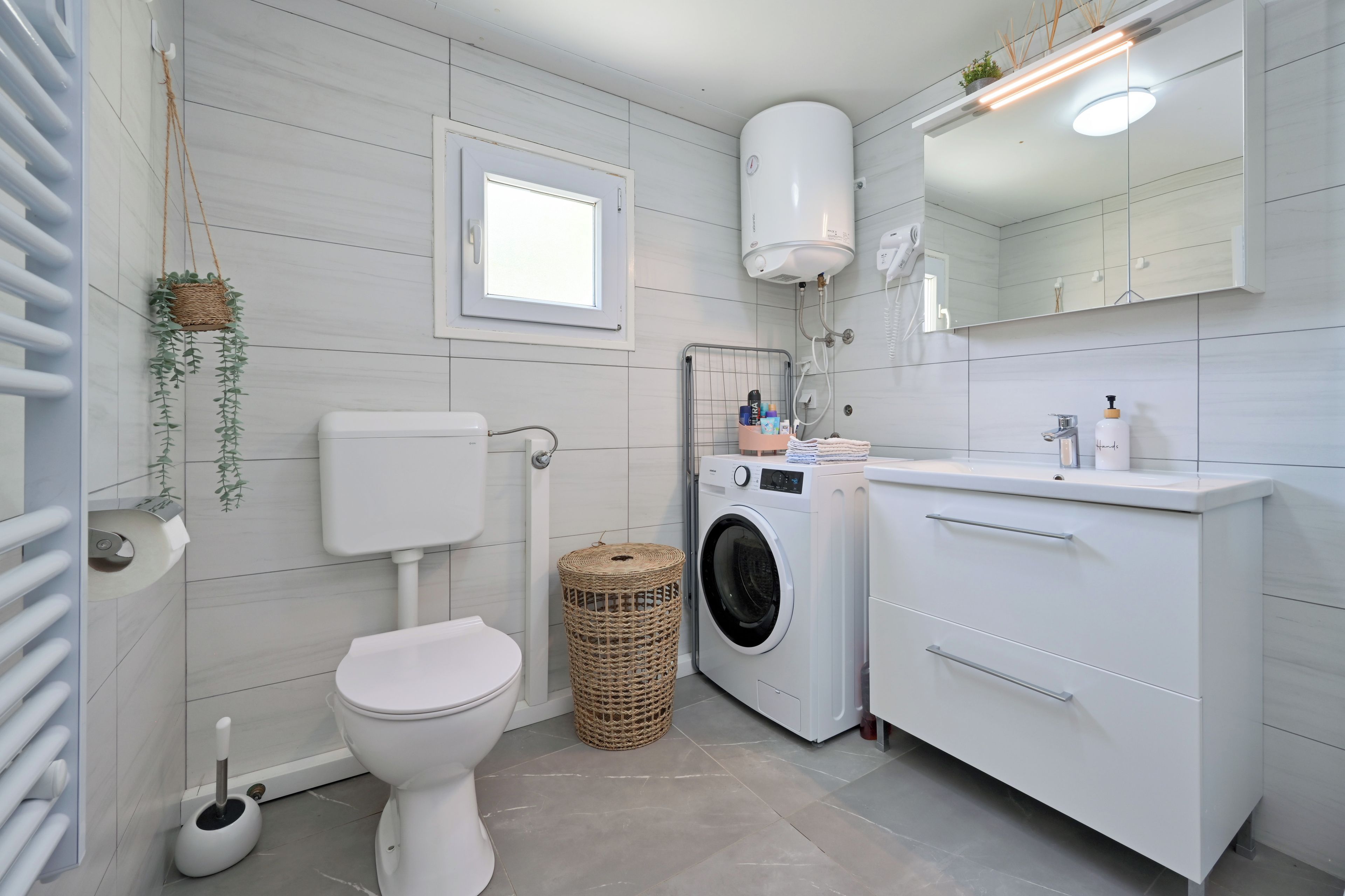 Un baño moderno con inodoro, lavadora y lavamanos con espejo.