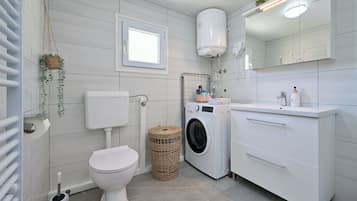 Un baño moderno con inodoro, lavadora y lavamanos con espejo.