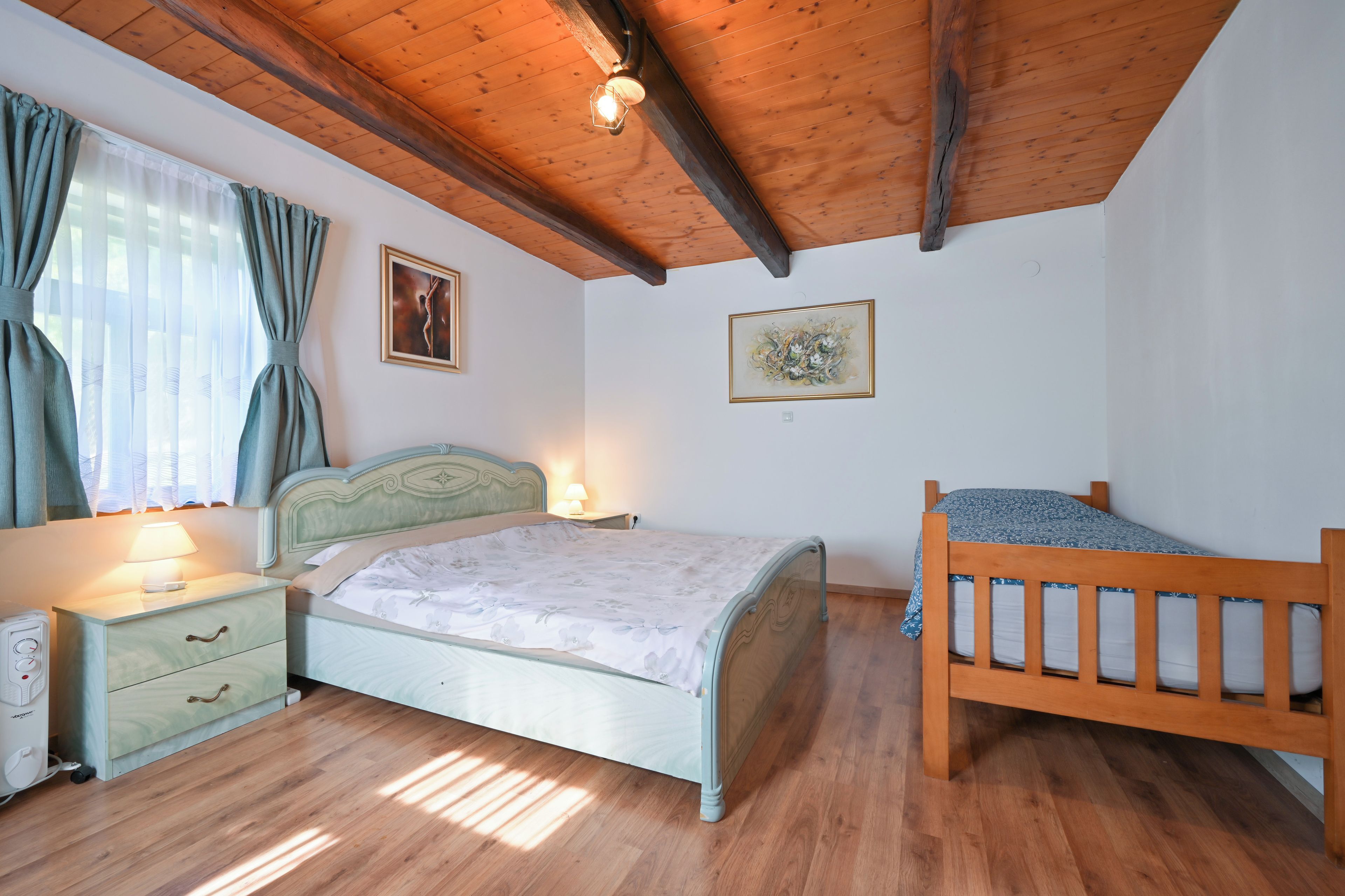 Ein Schlafzimmer mit Holzboden, einem Bett mit Blumenoptik, einem Nachttisch mit Lampe und einem weiteren kleinen Nachttisch mit Telefon.