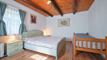 Ein Schlafzimmer mit Holzboden, einem Bett mit Blumenoptik, einem Nachttisch mit Lampe und einem weiteren kleinen Nachttisch mit Telefon.