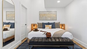 A modern bedroom with a large bed, a bench, a mirror, and a wall-mounted light fixture. - Summit Chalet by Avantstay Mountain Condo + Hot Tub + Fireplace + Near Park City & Deer Valley (Park City)