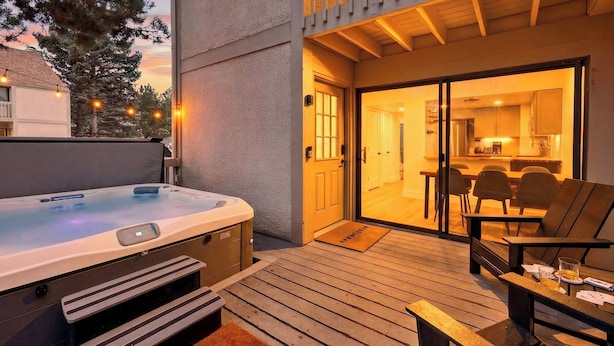 A hot tub on a wooden deck with a view of a kitchen and dining area through a glass door. - Summit Chalet by Avantstay Mountain Condo + Hot Tub + Fireplace + Near Park City & Deer Valley (Park City)