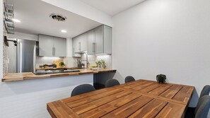 Una cocina moderna con armarios grises, una mesa de comedor de madera y una estufa empotrada.