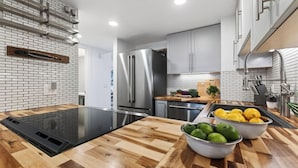 A modern kitchen with a black induction cooktop, stainless steel appliances, and a wooden countertop. - Summit Chalet by Avantstay Mountain Condo + Hot Tub + Fireplace + Near Park City & Deer Valley (Park City)