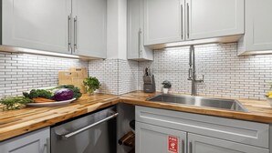 A modern kitchen with white cabinets, a wooden countertop, a stainless steel sink, and a fire safety sign. - Summit Chalet by Avantstay Mountain Condo + Hot Tub + Fireplace + Near Park City & Deer Valley (Park City)