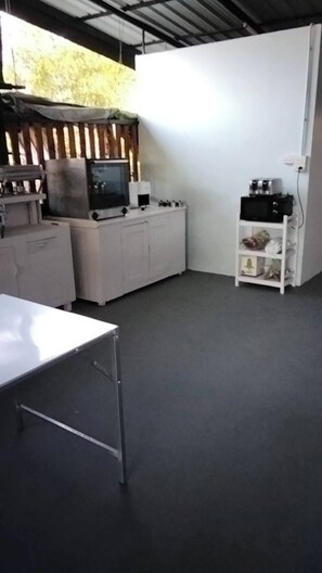A room with a white table, a white cabinet, a white shelf, and a white wall.