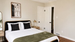 A bedroom with a bed, a nightstand, a lamp, a door, and a wall-mounted artwork. - 2-bedroom apartment in enjoyable University Heights (University Heights)
