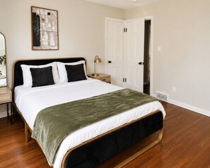 A bedroom with a bed, a nightstand, a lamp, a door, and a wall-mounted artwork. - 2-bedroom apartment in enjoyable University Heights (University Heights)
