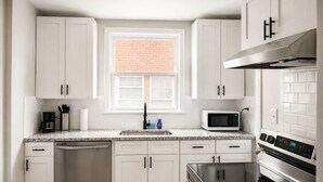 A modern kitchen with white cabinets, a built-in microwave, a stainless steel dishwasher, and a large oven. - 2-bedroom apartment in enjoyable University Heights (University Heights)