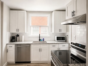 A modern kitchen with white cabinets, a built-in microwave, a stainless steel dishwasher, and a large oven. - 2-bedroom apartment in enjoyable University Heights (University Heights)