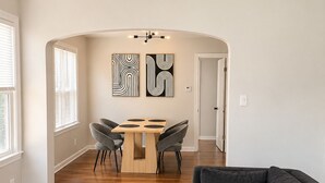 A modern living room with a dark gray sectional sofa, a round marble coffee table, and a dining area with a wooden table and chairs. - 2-bedroom apartment in enjoyable University Heights (University Heights)