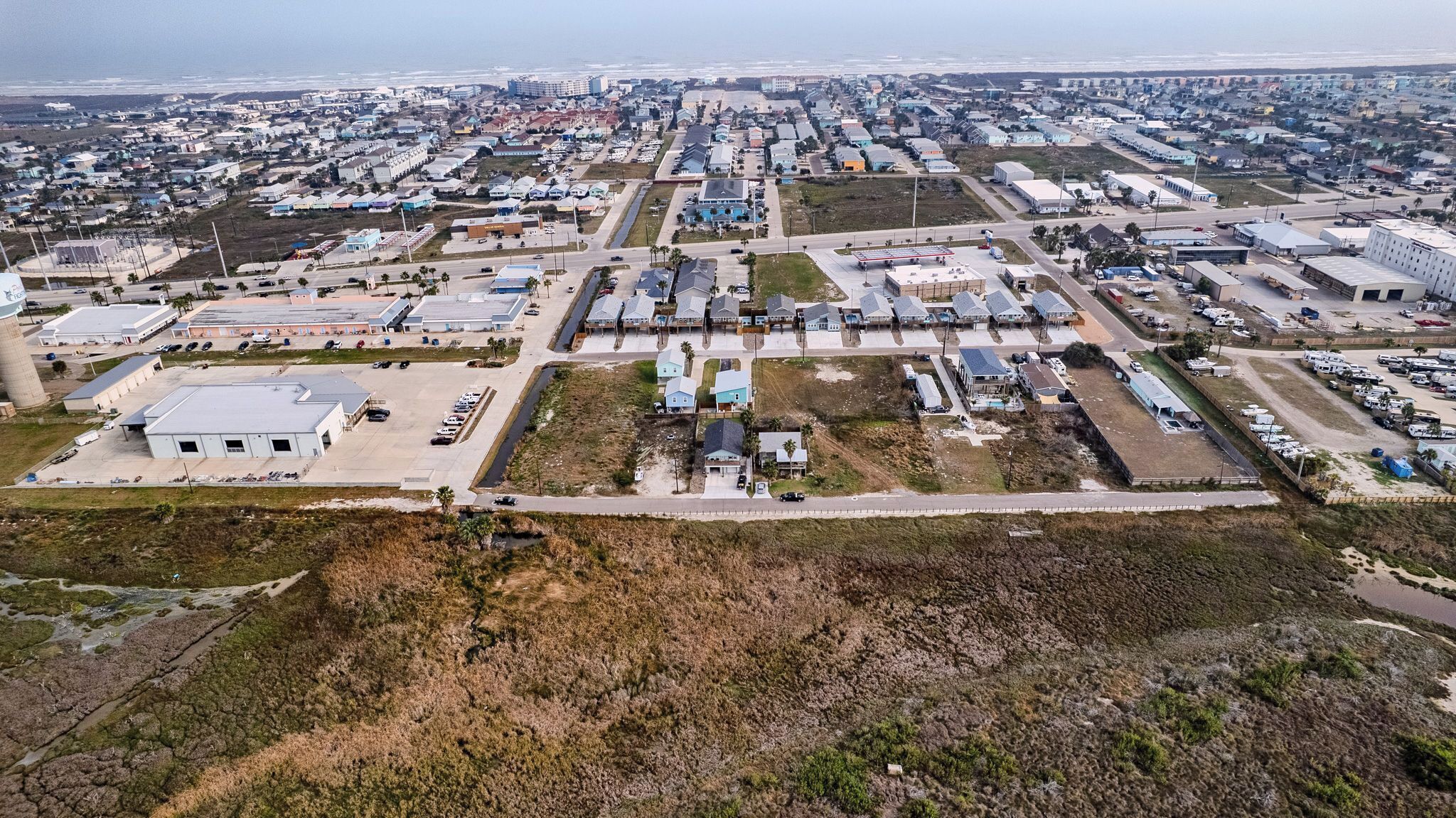 Vue aérienne d’un quartier résidentiel avec des maisons, un grand bâtiment industriel et un parking.