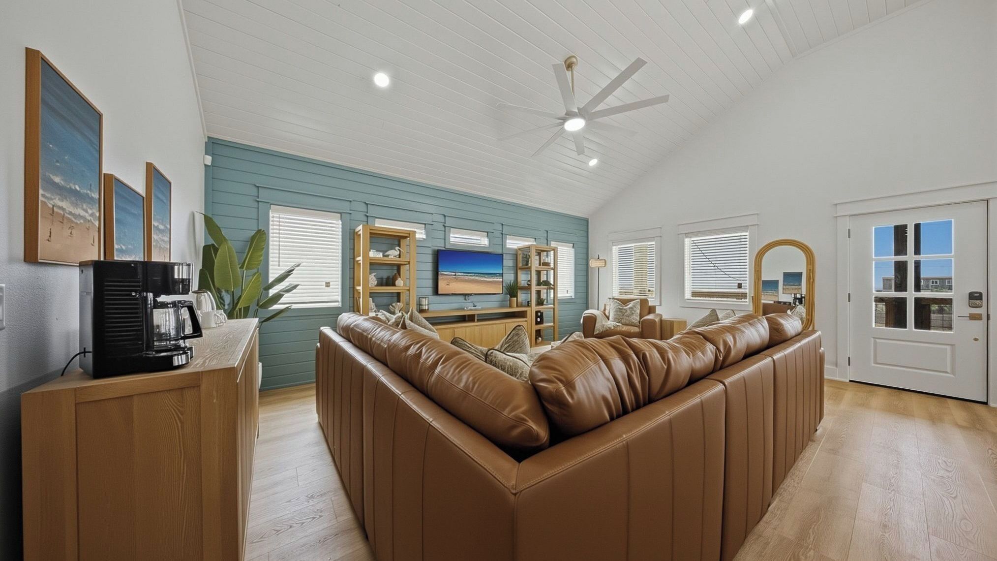 A spacious living room with a large leather sofa, a coffee station, a television, and a ceiling fan.