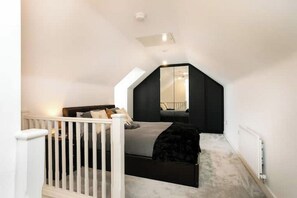 A compact bedroom with a sloped ceiling, a bed, a white railing, and a radiator. - Countryside Comfort near Sharphill Woods (Nottinghamshire)