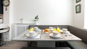 Et moderne spiseområde med et bord dækket til morgenmad, inklusive croissanter og appelsinjuice.