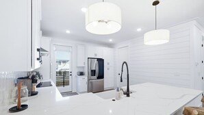 A modern kitchen with white cabinetry, a large island with a sink, and stainless steel appliances. - Luxury Townhome, close to the Bay, short drive to the Beach, Sleeps 10 (Santa Rosa Beach)