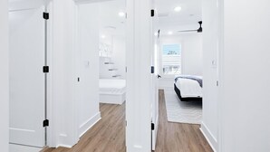 A modern, white-walled hallway leading to a bedroom with a bed and a window. - Luxury Townhome, close to the Bay, short drive to the Beach, Sleeps 10 (Santa Rosa Beach)