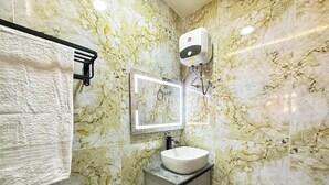 Een badkamer met een marmeren wand, een wastafel, een handdoekhouder en een handdroger.