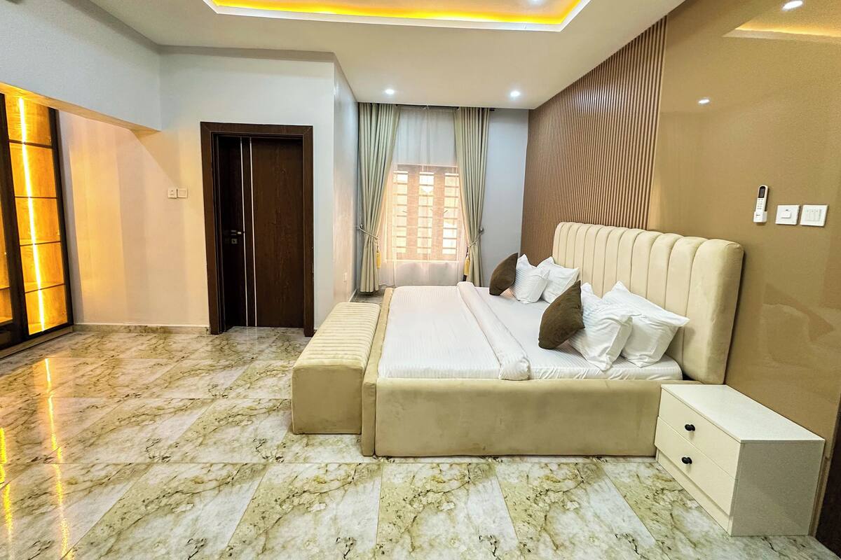 A modern bedroom with a large bed, bedside tables, a built-in wardrobe, and a ceiling with recessed lighting.