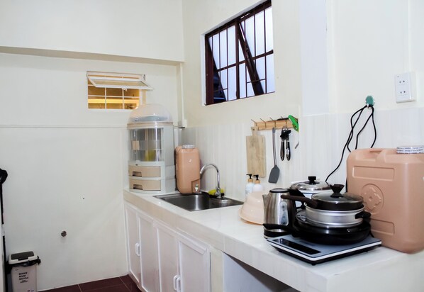 A kitchen with a sink, countertop, and various appliances including a coffee maker, kettle, and blender. - Cozy 2-bedroom house in amazing Legazpi City with AC, Fast Wifi & Kitchen (Legazpi City)