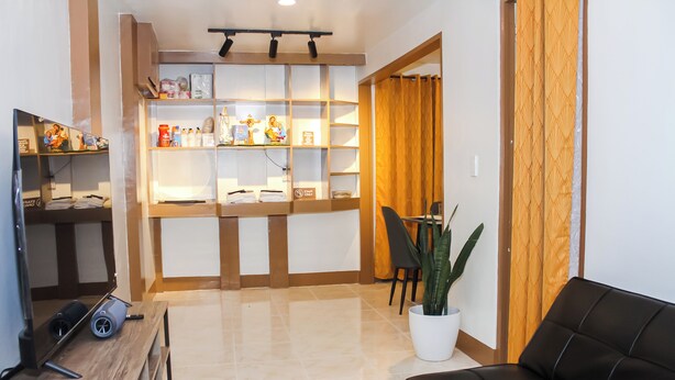 A living room with a sofa, a coffee table, a TV, a bookshelf, and a potted plant. - Cozy 2-bedroom house in amazing Legazpi City with AC, Fast Wifi & Kitchen (Legazpi City)