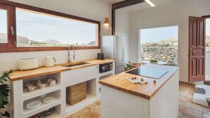 Eine moderne Küche mit integrierter Kochinsel, Holzarbeitsplatten und Blick ins Freie.
