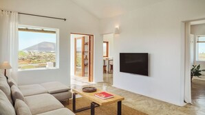 Ein modernes Wohnzimmer mit einer Couch, einem Couchtisch, einem Flachbildfernseher und Blick auf einen Berg.