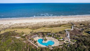 Oversigtsbillede af et resort med swimmingpool, adgang til stranden og krystalklart hav.