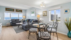 A living room with a sofa, a dining table with chairs, a fireplace, and a view of the ocean. - Oceanfront Condo in Amelia Island Plantation with Pool (Fernandina Beach)