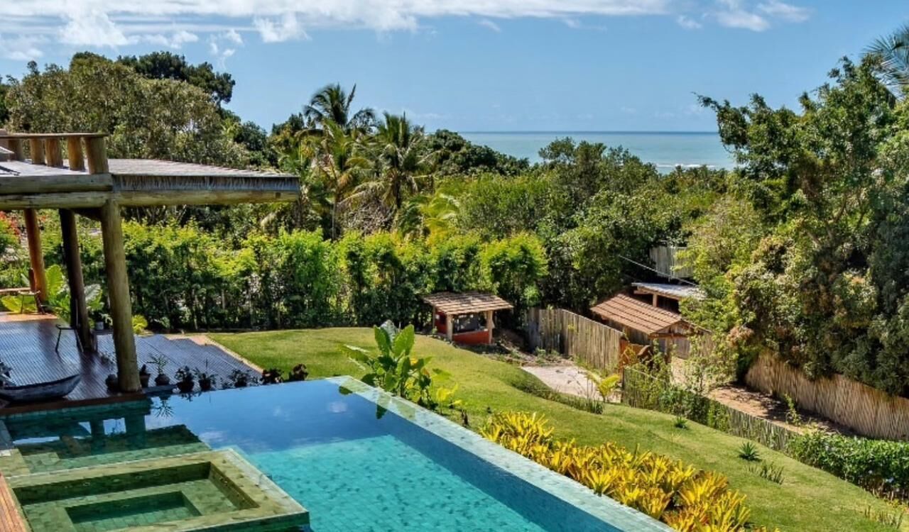 Un jardin avec une piscine, une terrasse en bois et une vue sur l’océan.