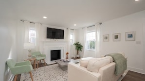 Una sala de estar moderna con chimenea, un sofá, un televisor y una mesa de centro.