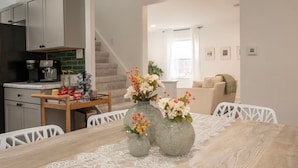 Cocina moderna con comedor que incluye una mesa de madera y mantel de encaje.