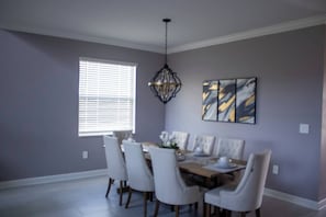 Ein Esszimmer mit einem Tisch für sechs Personen, einer Chandelier und einem Fenster mit Jalousien.