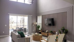 Un salon spacieux avec un canapé, des fauteuils, un téléviseur et une grande fenêtre.