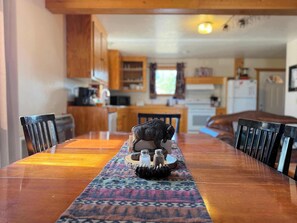Una mesa de madera para comer con sillas, un camino de mesa estampado y un salero como centro de mesa.