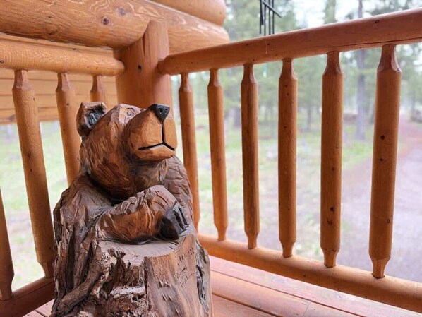Eine hölzerne Bärenskulptur auf einem Holzpfosten.
