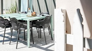 An outdoor patio with a table and chairs, a bottle of water, and a menu. - Kent House | Luxury heritage home, Prime location (Albany)