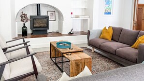 A modern living room with a fireplace, a sofa, a coffee table, and a hanging light fixture. - Kent House | Luxury heritage home, Prime location (Albany)