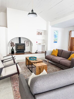 A modern living room with a fireplace, a sofa, a coffee table, and a hanging light fixture.