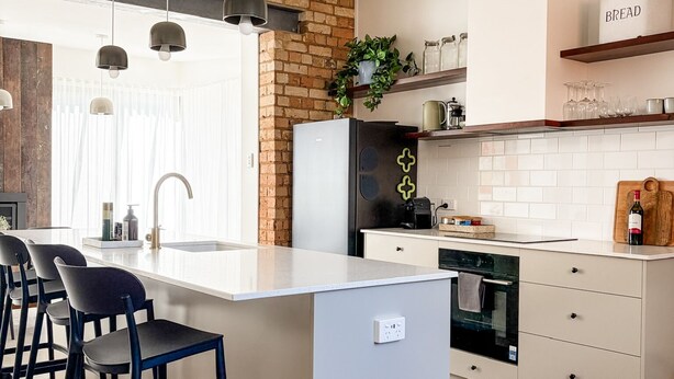 A modern kitchen with a central island, bar stools, a refrigerator, and a coffee machine. - Kent House | Luxury heritage home, Prime location (Albany)