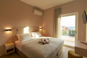 Une chambre d’hôtel équipée d’un lit, de tables de chevet, d’un climatiseur, d’une télévision et d’un balcon avec vue.