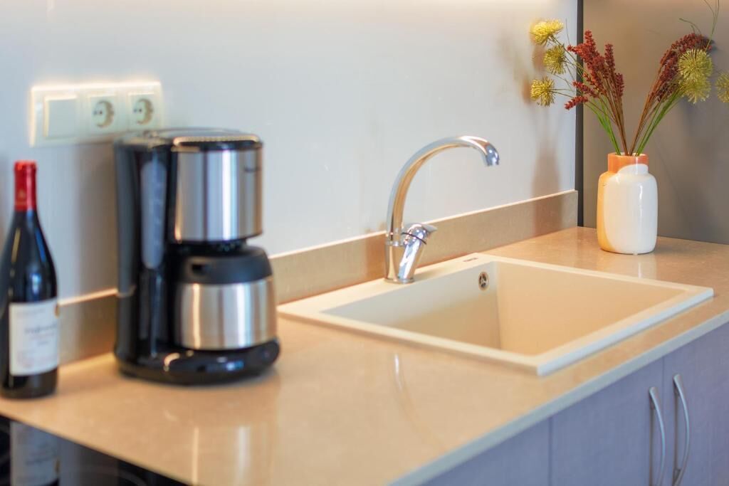 A kitchen with a coffee maker, a wine bottle, and a vase with flowers on the counter.